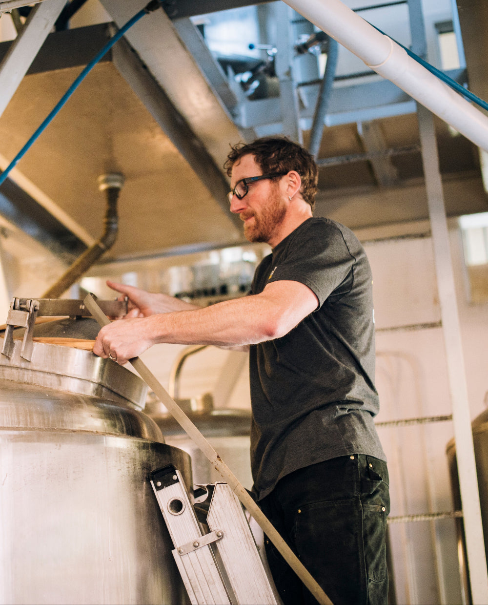 Person working on a large metal tank in an industrial setting