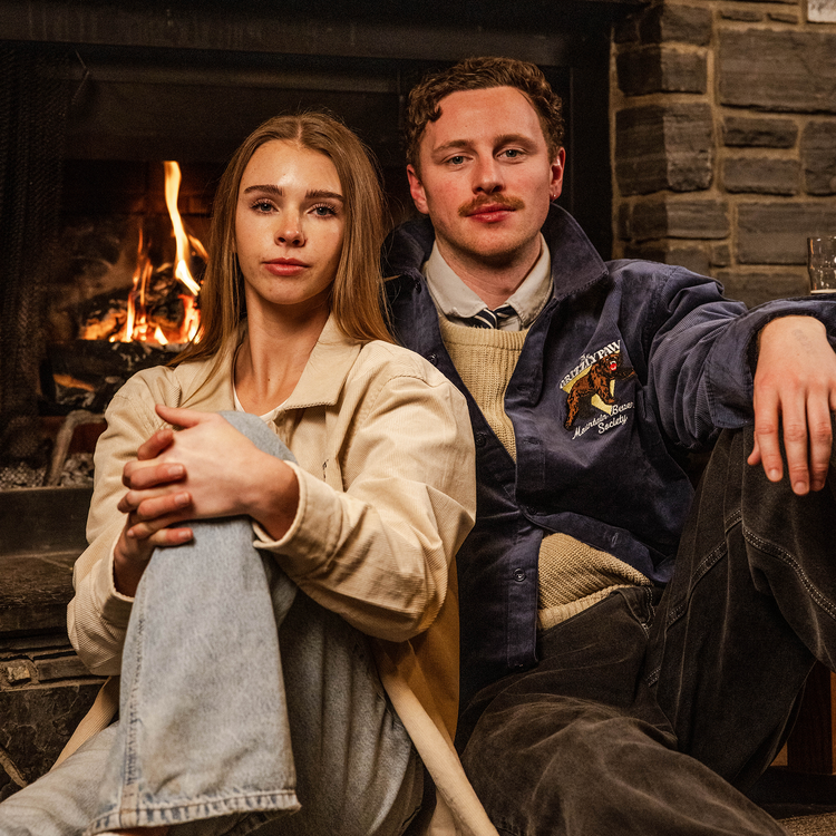 Two people sitting in front of a fireplace with a warm fire.