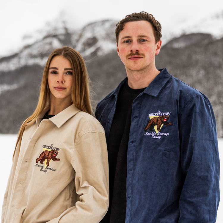Two people wearing jackets with bear emblems in a snowy landscape